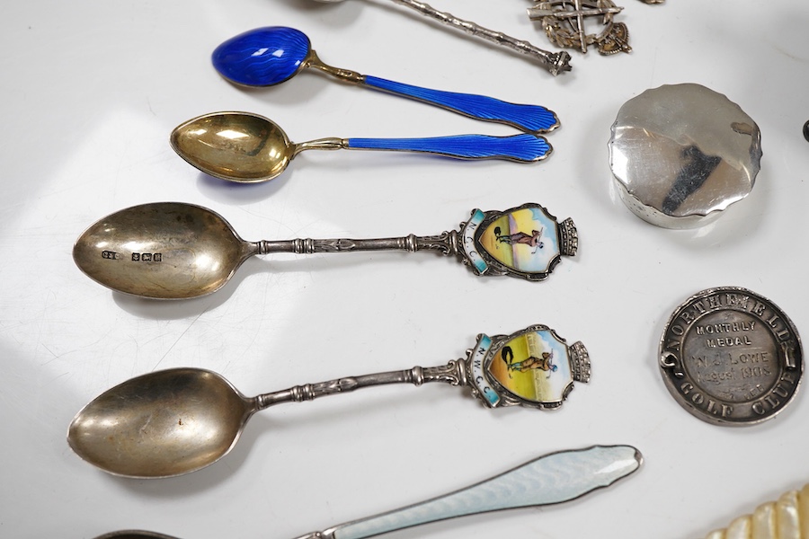 Assorted silverware including a late Victorian mother of pearl handled butter knife, a George V pill box, an Edwardian mustard pot with plated spoon, two enamelled golf related spoons, a rifle shooting related spoon, six